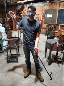 Samir Khalil holding a 6-foot fire poker he made